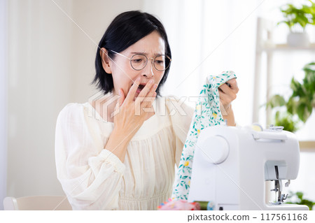 Hobby: Middle-aged woman sewing with a sewing machine Hobby: Middle-aged woman sewing with a sewing machine 117561168
