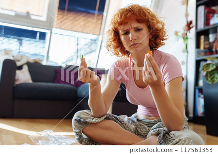 teenage girl assembles construction set according to instructions sitting on floor in room teenage girl assembles construction set according to instructions sitting on floor in room 117561353