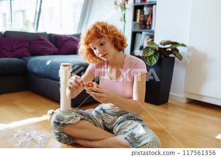 teenage girl assembles construction set according to instructions sitting on floor in room teenage girl assembles construction set according to instructions sitting on floor in room 117561356