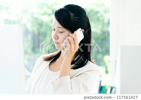 A woman talking on a smartphone with documents in her hands 117561427