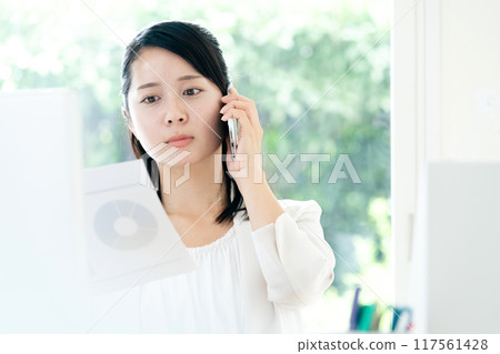 一位女士手拿文件在智慧型手機上交談 117561428