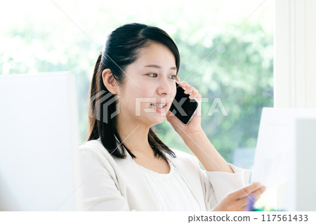一位女士手拿文件在智慧型手機上交談 117561433