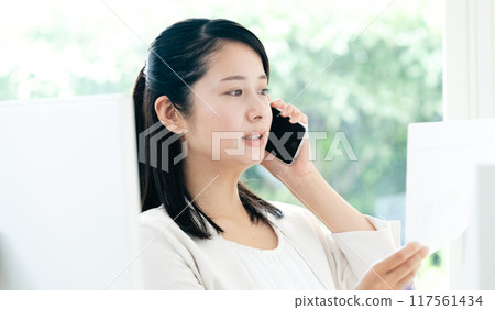 一位女士手拿文件在智慧型手機上交談 117561434