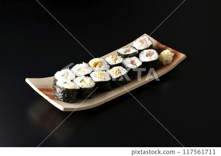 Assorted sushi rolls photographed against a black background 117561711