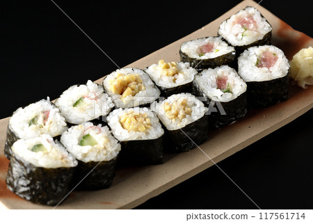Assorted sushi rolls photographed against a black background 117561714