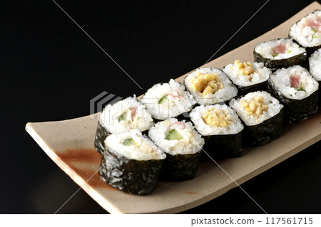 Assorted sushi rolls photographed against a black background 117561715