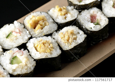 Assorted sushi rolls photographed against a black background Assorted sushi rolls photographed against a black background 117561717