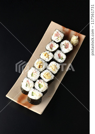 Assorted sushi rolls photographed against a black background 117561731
