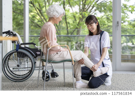 Senior woman undergoing rehabilitation and staff in white coats 117561834
