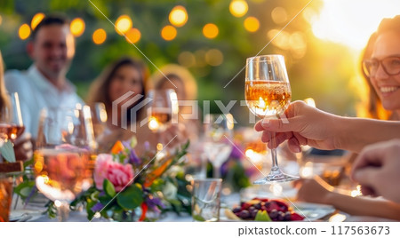 A group of friends toasting with wine glasses at an outdoor dining table, celebrating the joy and connection during social gatherings 117563673