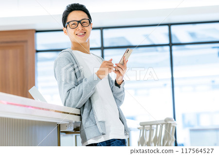 A man touching a smartphone in the office Photo cooperation: WEEK Shibadaimon (Sun Frontier Fudousan) 117564527