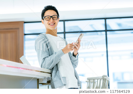 A man touching a smartphone in the office Photo cooperation: WEEK Shibadaimon (Sun Frontier Fudousan) 117564529