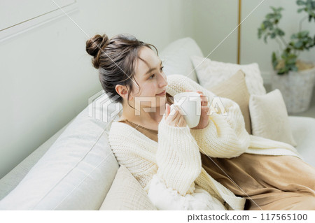 Woman drinking hot coffee in her room Woman drinking hot coffee in her room 117565100
