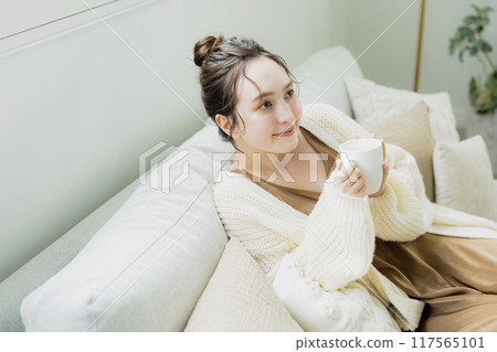 Woman drinking hot coffee in her room Woman drinking hot coffee in her room 117565101