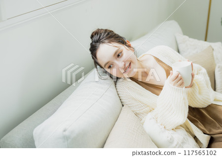 Woman drinking hot coffee in her room Woman drinking hot coffee in her room 117565102