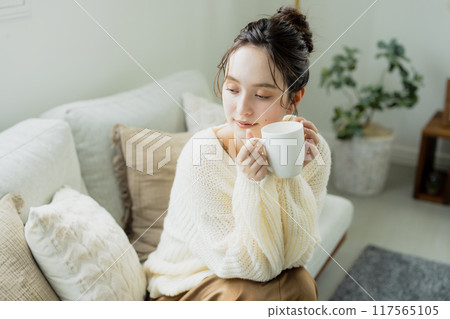 Woman drinking hot coffee in her room 117565105