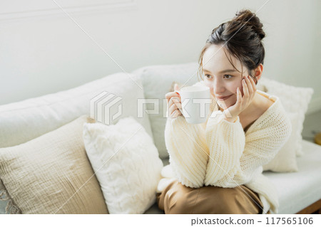 Woman drinking hot coffee in her room 117565106