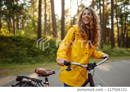 Young woman in yellow coat riding bicycle park. Active day. Young woman in yellow coat riding bicycle park. Active day. 117566152