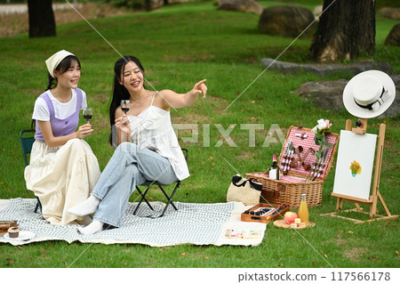 Cheerful asian female friends having fun on the picnic at the park 117566178