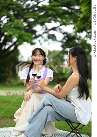 Happy young lesbian couples having fun outdoor and toasting with wine glasses at picnic 117566185