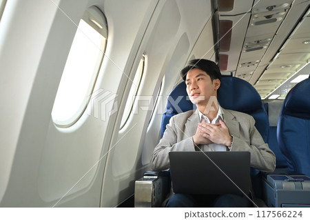 Scared male passenger looking out the window, feeling terrified while traveling by plane 117566224