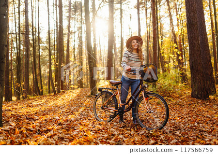 Happy active young woman on bike in autumn park at sunset. Concept of people, recreation, active lifestyle. 117566759