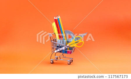 Shopping trolley with stationery items and school supplies on orange background. back to school and education background concept. Shopping cart, supermarket trolley with school supplies. Preparing for Shopping trolley with stationery items and school supplies on orange background. back to school and education background concept. Shopping cart, supermarket trolley with school supplies. Preparing for 117567173