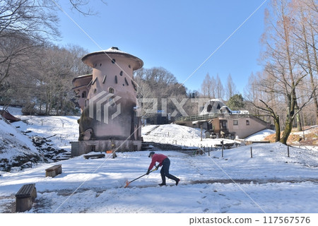 Snow falls in Akebono Children's Forest Park, and under a clear blue sky, children are clearing snow in front of the Mushroom House. 117567576