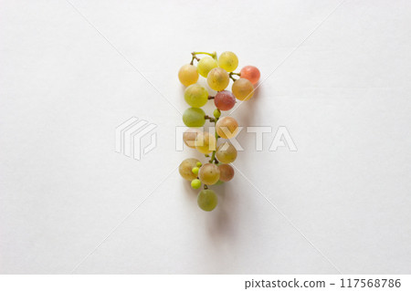A bunch of mismatched grapes placed in the center of a landscape white sheet of paper 117568786