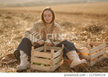 Beautiful woman taking pictures in the autumn field. Autumn harvest. Lifestyle concept. 117569129