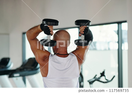 Muscular Man Lifting Dumbbells In Fitness Club 117569735