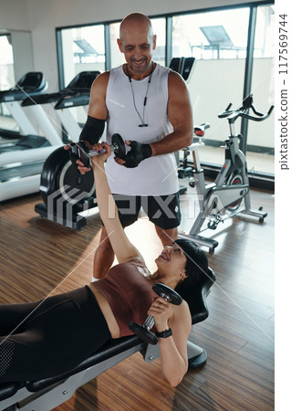 Woman Lifting Dumbbells With Instructor 117569744