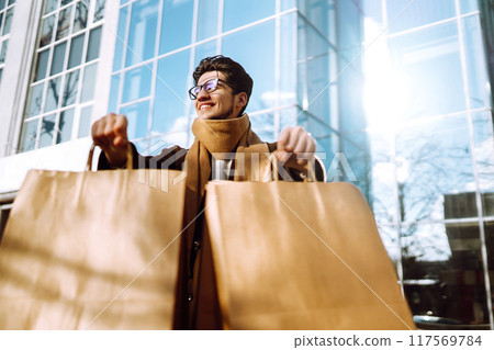 Stylish man with paper packages after shopping. Sale, consumerist, lifestyle concept. 117569784