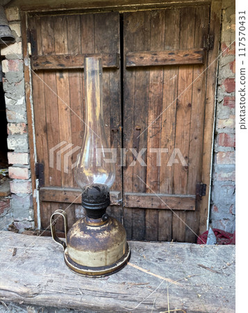 An old kerosene lamp with a glass shade. Inside a room covered with slate. An old kerosene lamp with a glass shade. Inside a room covered with slate. 117570431