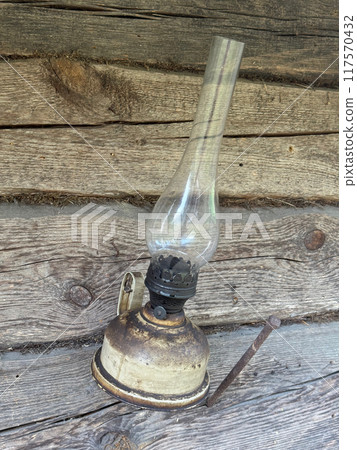 A kerosene lamp hangs on the wall of an old log shed. 117570432