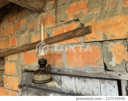 A kerosene lamp hangs on the wall of a brick shed. A kerosene lamp hangs on the wall of a brick shed. 117570440