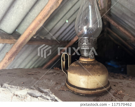 An old kerosene lamp with a glass shade. Inside a room covered with slate. An old kerosene lamp with a glass shade. Inside a room covered with slate. 117570462