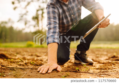 The farm owner's hand touches soil, checks quality of the soil before sowing. Ecology, technology. 117570660