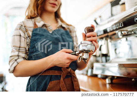 An experienced female bartender prepares a hot drink. Takeaway food. Professional coffee making. An experienced female bartender prepares a hot drink. Takeaway food. Professional coffee making. 117570777