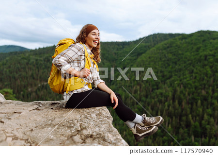 Beautiful woman with backpack admires view from top of mountain. Mountain tourism. Beautiful woman with backpack admires view from top of mountain. Mountain tourism. 117570940