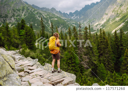 Happy woman with a yellow hiking backpack enjoying the mountain landscape. Travel concept. Happy woman with a yellow hiking backpack enjoying the mountain landscape. Travel concept. 117571268