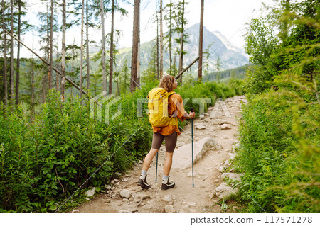 Stylish tourist woman with yellow backpack against backdrop of mountain scenery. Concept of travel. Stylish tourist woman with yellow backpack against backdrop of mountain scenery. Concept of travel. 117571278