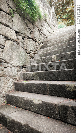 An ancient stone staircase leading upwards. The concept of a difficult rocky path to success, overcoming difficulties. An ancient stone staircase leading upwards. The concept of a difficult rocky path to success, overcoming difficulties. 117571335