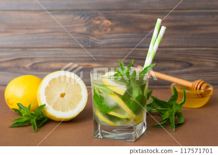 Mojito cocktail. Refreshing mojito cocktail with lime, lemon and mint in a tall glass with a stick Mojito cocktail. Refreshing mojito cocktail with lime, lemon and mint in a tall glass with a stick 117571701