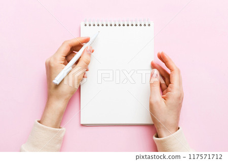 Woman hand with pencil writing on notebook. Woman working on office table. Female hand holding pencil and sketchbook. Mock-up Concept 117571712