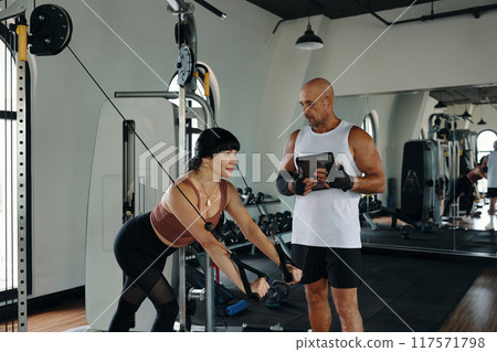 Woman Lifting Weights With Personal Instructor 117571798