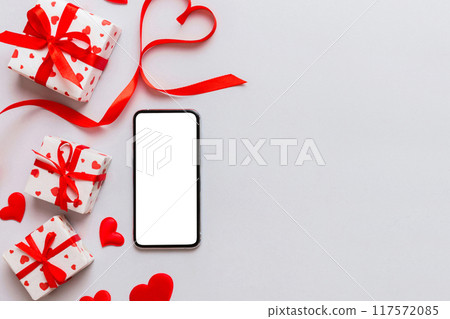 mobile phone with blank screen on colored background with hearts, valentine day concept top view flat lay 117572085
