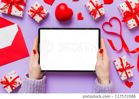 Female hands using a laptop for Valentine day background, gift box and envelope, hearts 117572086