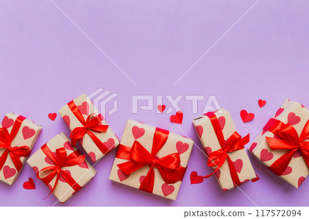 Top view photo of valentine day decorations gift box with red ribbon bow on colored background. Holiday gift boxes with top view 117572094