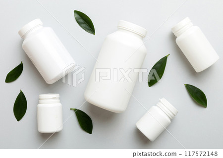 supplement pills with medicine bottle health care and medical top view. Vitamin tablets. Top view mockup bottle for pills and vitamins with green leaves, natural organic bio supplement, copy space 117572148